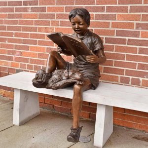 Junge liest mit Hundestatue