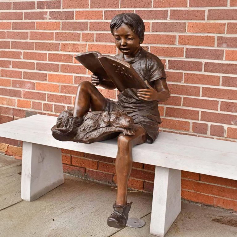 Junge liest mit Hundestatue