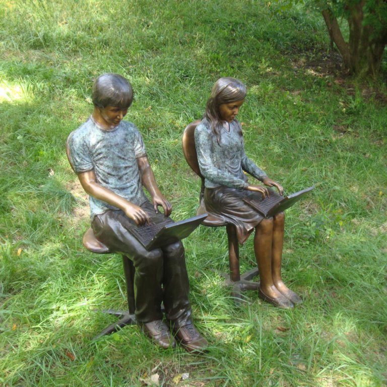 Junge und Mädchen mit Laptop-Statue