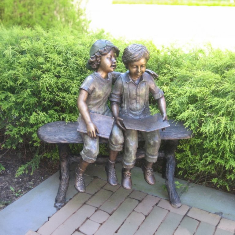 Statue von zwei Jungen auf einer Bank