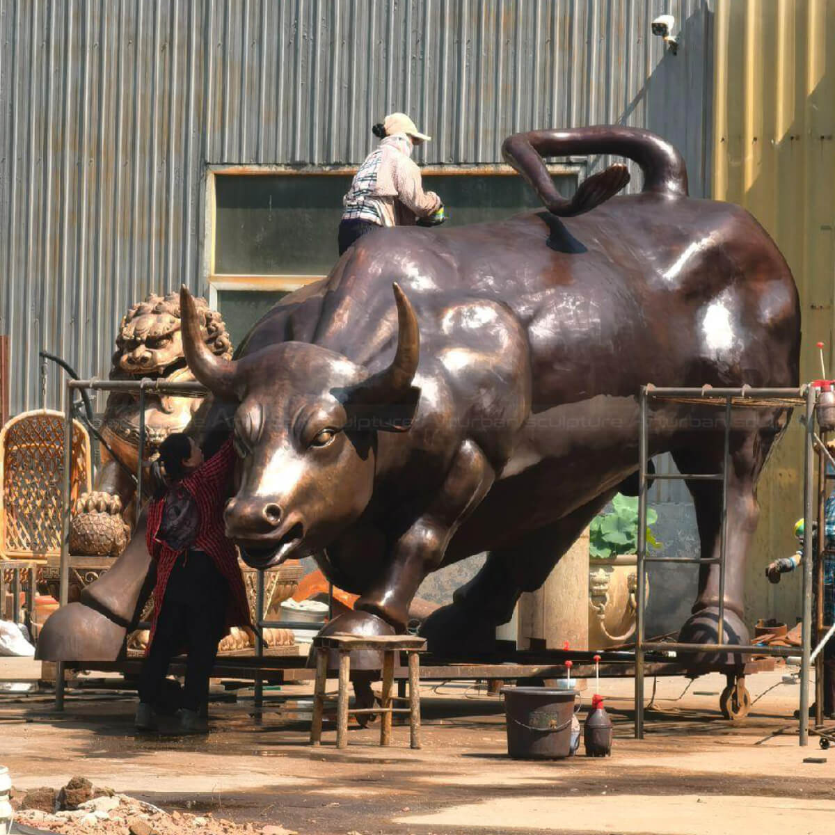 Big Bull Wall Street sculpture being polished with wax by workers.