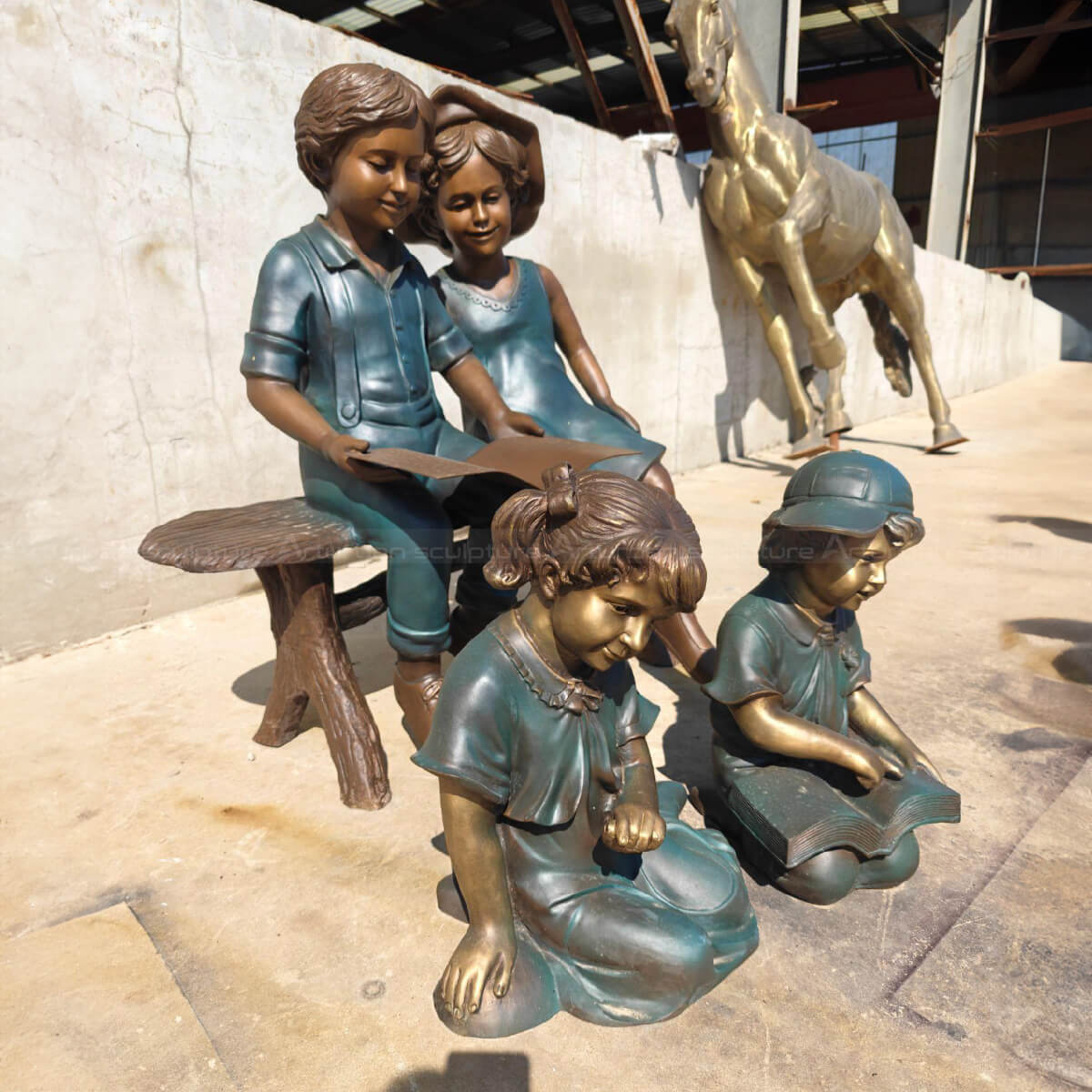 Children Reading Statue, two sitting on a bench and two crouching on the ground