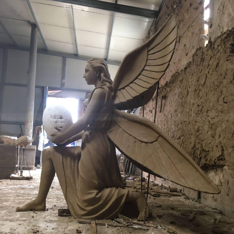 Clay mold of kneeling angel statue holding an egg.