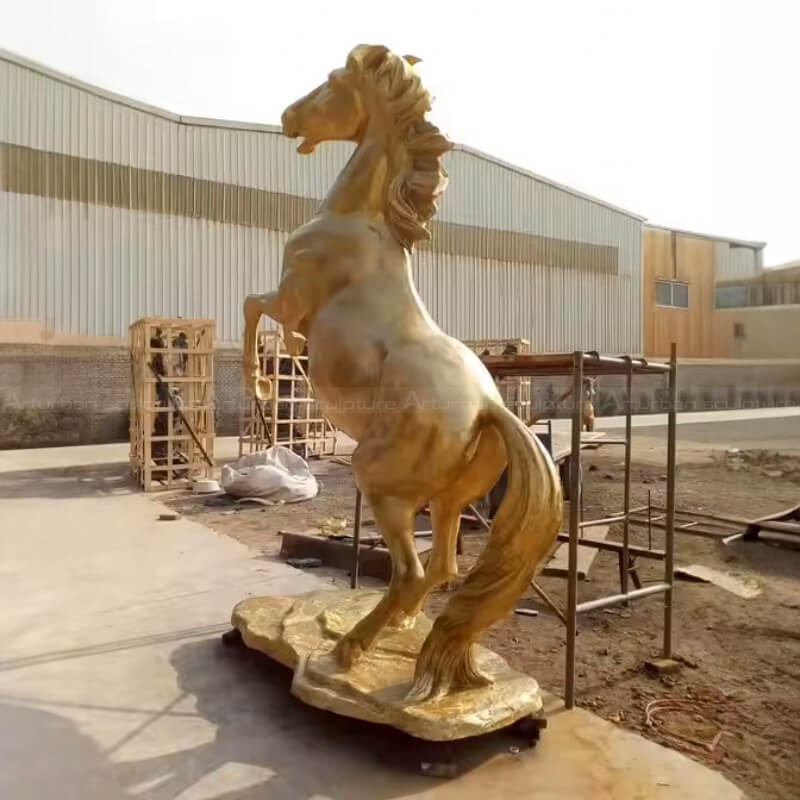 Golden Horse Sculpture mid-leap with raised front legs and flowing mane and tail