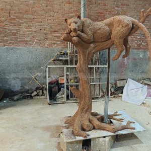 Grande statue de jaguar allongée sur une branche d'arbre