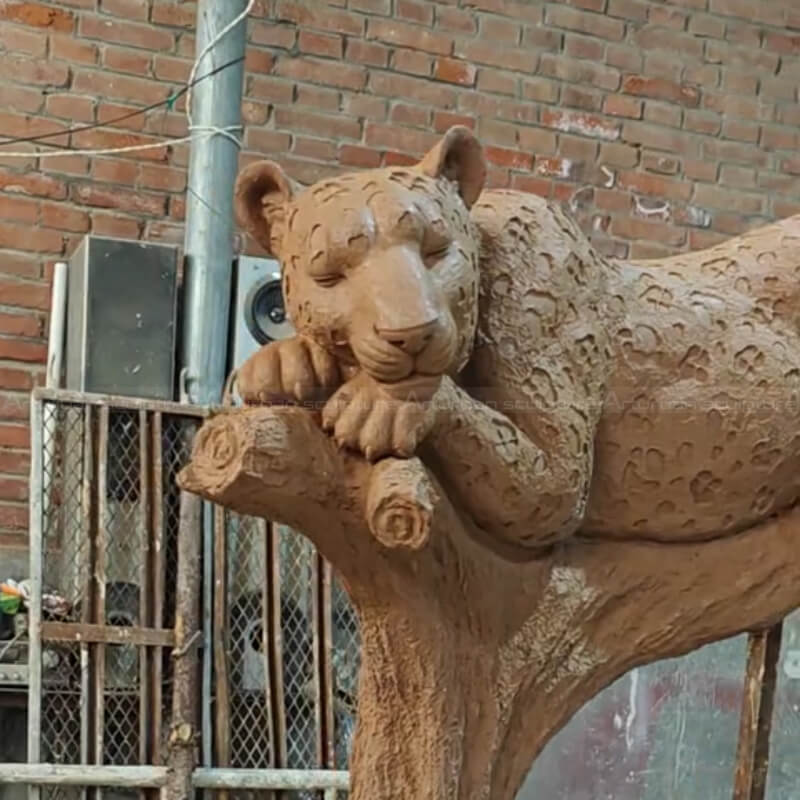 Grande statue de jaguar reposant sur un arbre