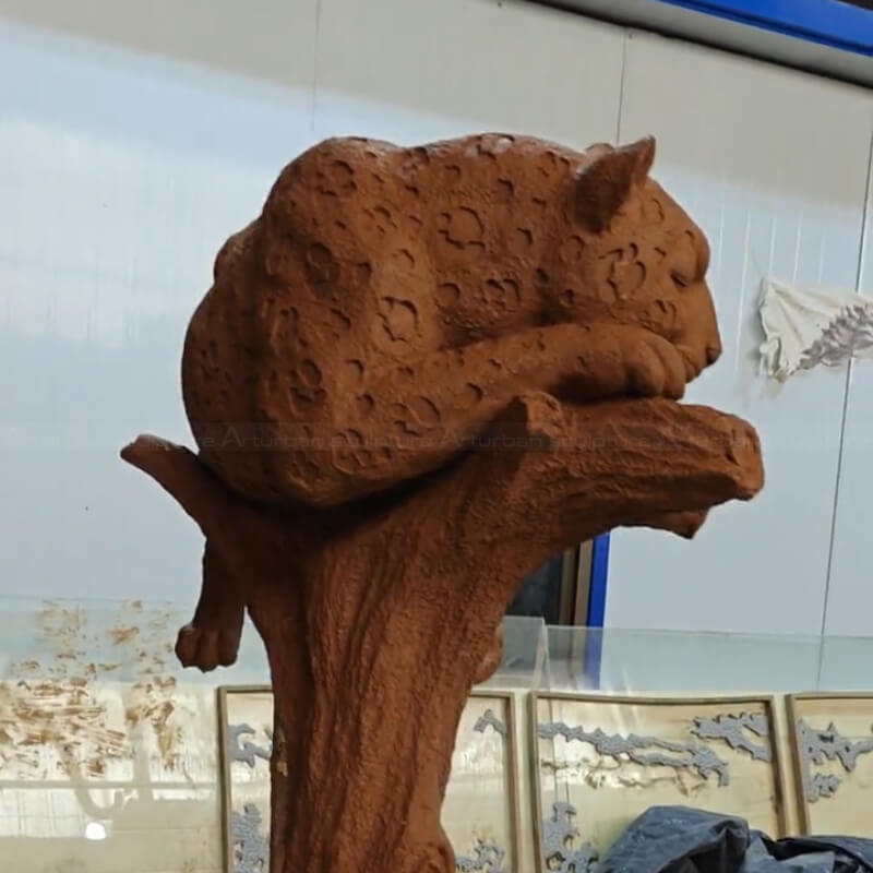 sculpture en argile d'un grand jaguar reposant sur un arbre