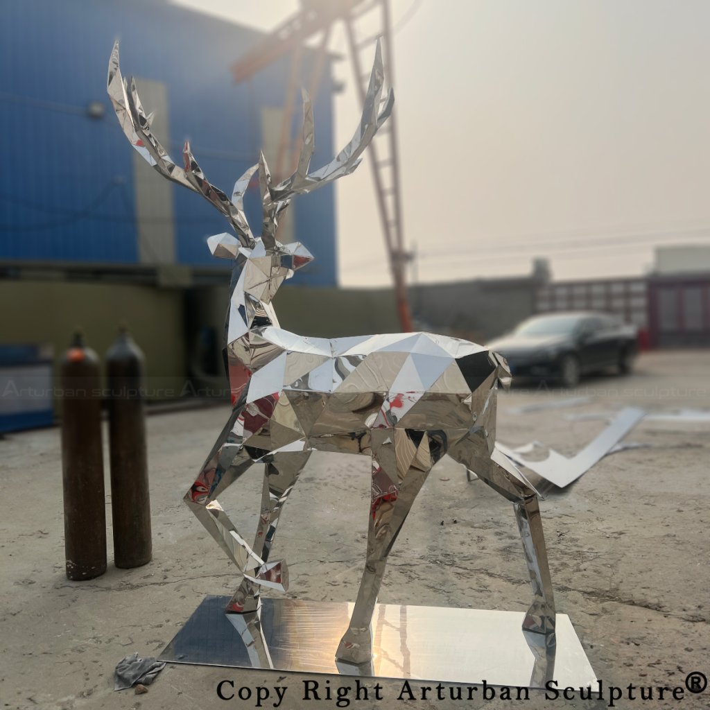 reflective stainless steel deer sculpture standing on a rectangular base