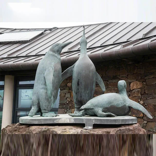 Bronzene Pinguin-Statue zeigt einen stolz stehend, einen ruhend und den anderen natürlich stehend