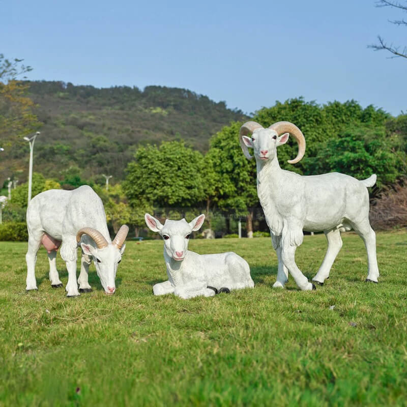 Außen-Ziegenstatue aus Faserverglas mit zwei stehenden erwachsenen Ziegen und einem liegenden Lamm auf dem Gras