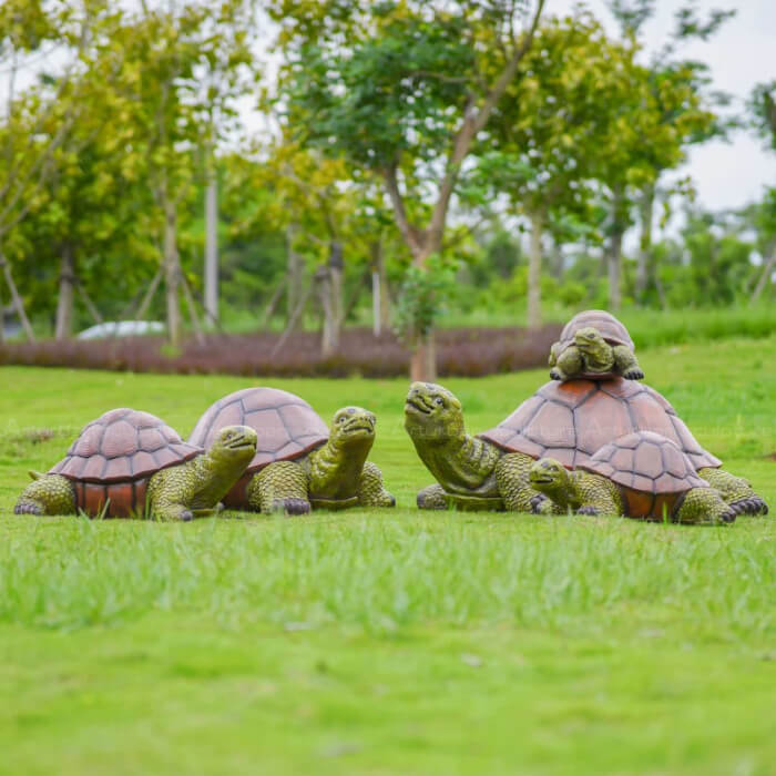 Décor de jardin tortue montrant plusieurs tortues rassemblées avec un bébé tortue reposant sur le dos d'une plus grande