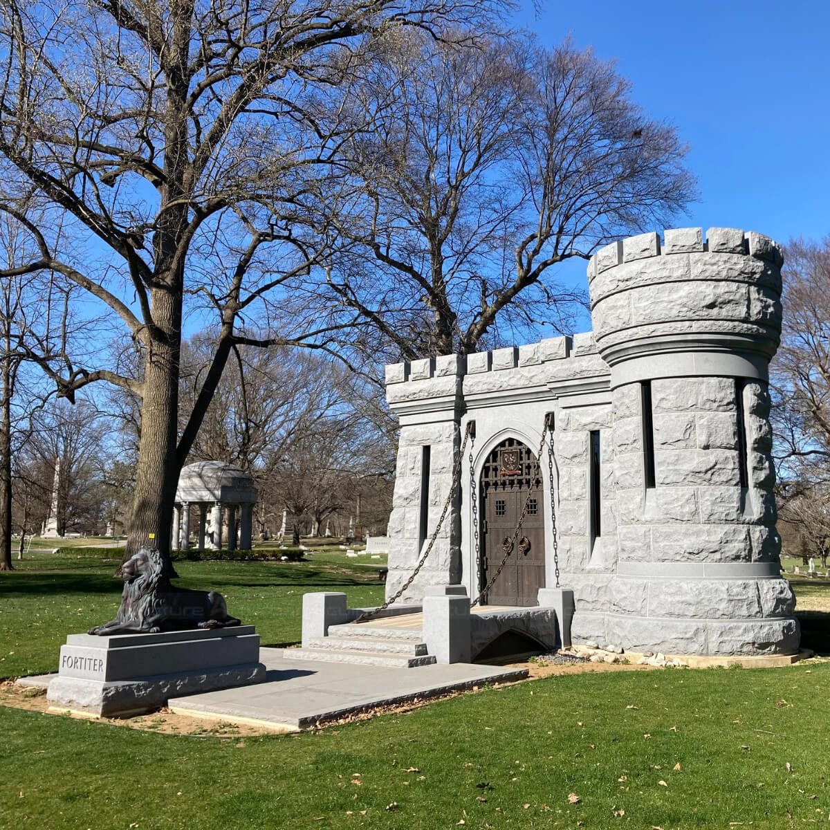 reclining Guardian Lion Statue placed in front of a fortress-style mausoleum at Crown Hill Cemetery