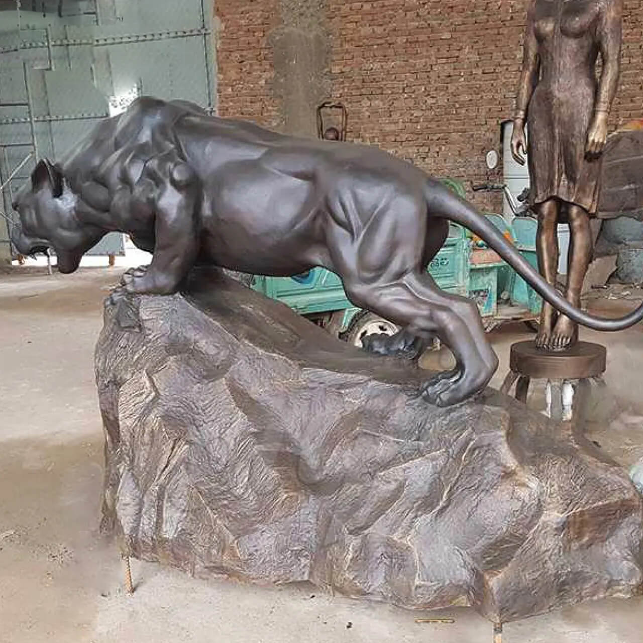 vista laterale della Statua di Pantera in Bronzo in piedi su una roccia con la bocca aperta e i denti affilati visibili