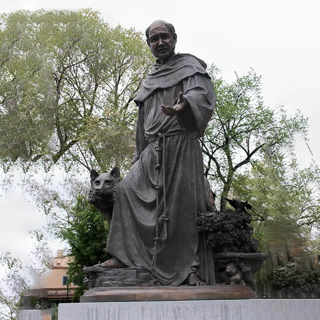 bronze St Francis and the Wolf Statue depicting St. Francis with an outstretched hand and a wolf beside him