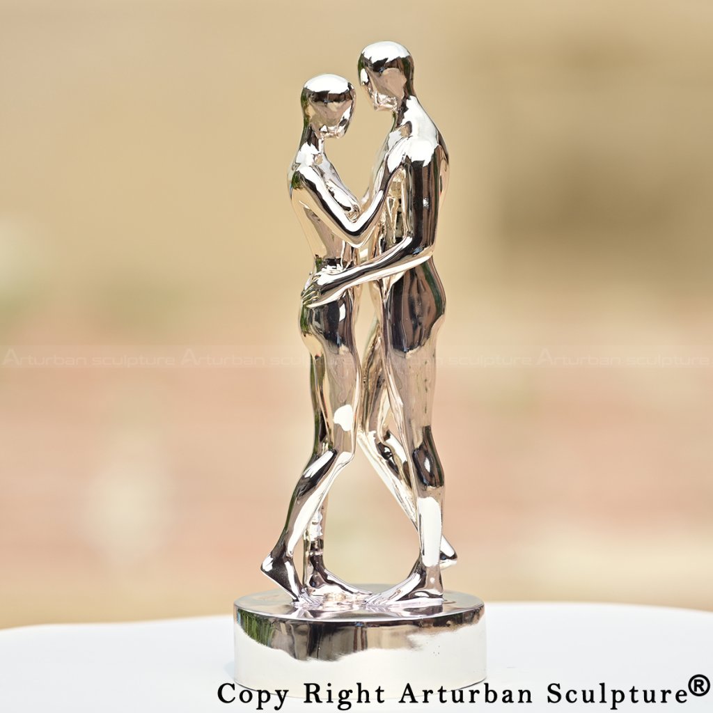 Statua di coppia abbracciata intitolata In Ogni Vita Ti Troverò, superficie metallica riflettente