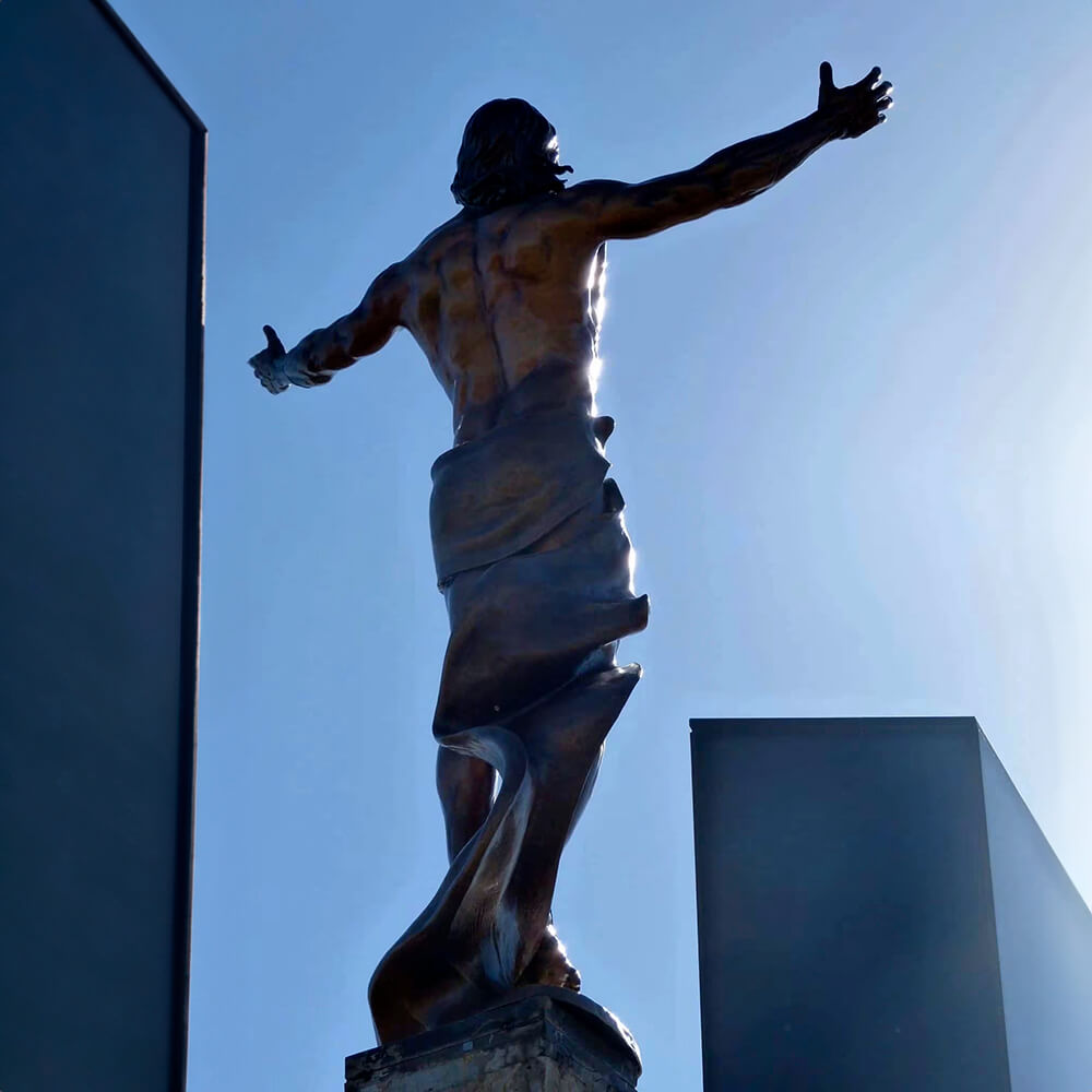 Vista traseira da Escultura da Ressurreição de Jesus mostrando a túnica fluida e os braços abertos