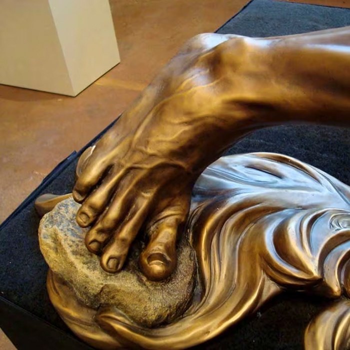 Close-up of Jesus' bronze foot on stone in Baptism Statue