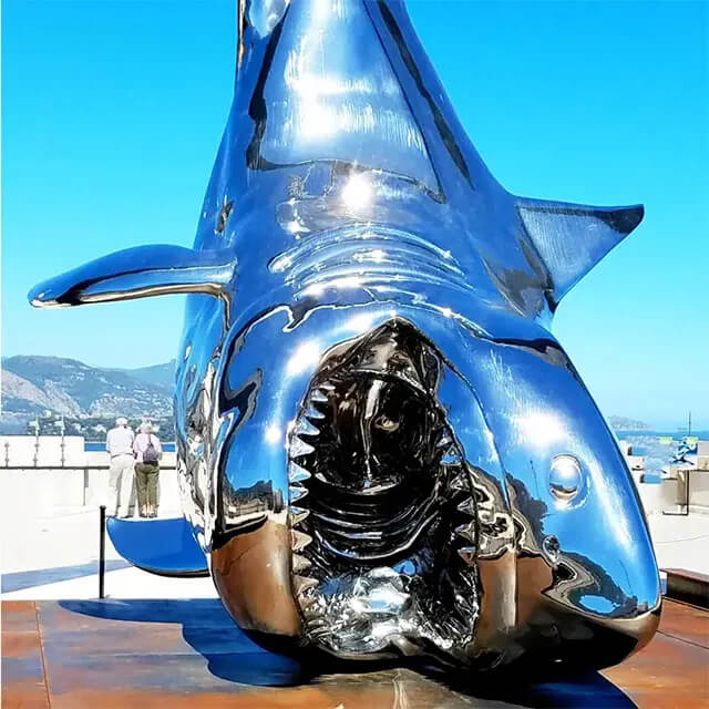 Primo piano della scultura di squalo sospesa in acciaio inossidabile con fauci aperte