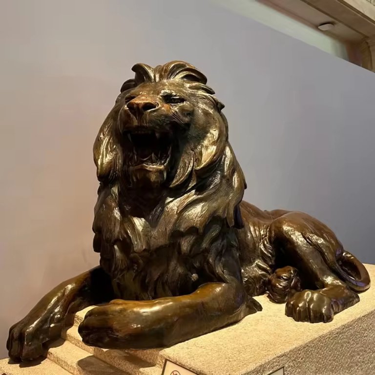 Statue en bronze d'un lion couché avec une expression rugissante