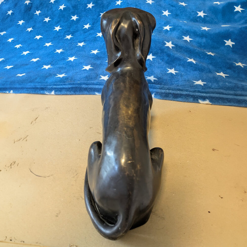 Bronzene Dackel-Gedenkstatue, die den länglichen Körper und den eingewickelten Schwanz des Hundes zeigt