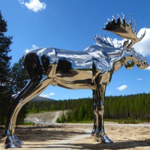 The Big Elk Statue in stainless steel, giant moose sculpture reflecting sky and forest in Norway