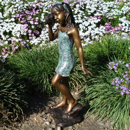 Estatua de bronce de niña escuchando una concha en el jardín