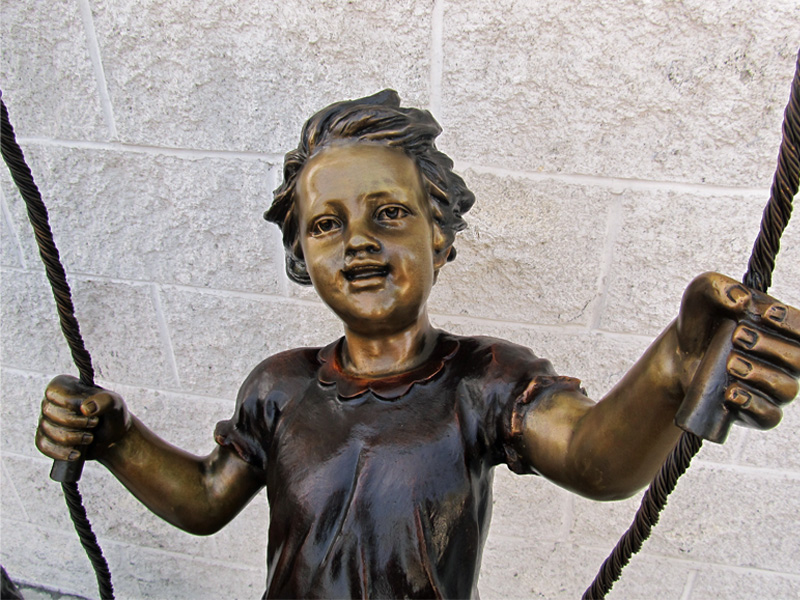 Bronze Girl on Swing Statue smiling closeup