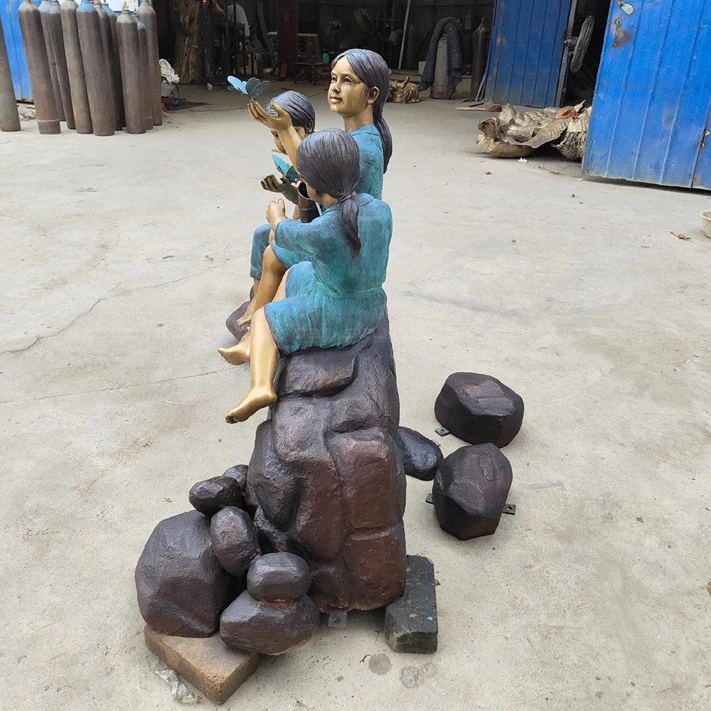 Estatua de niños sentados sobre un tronco