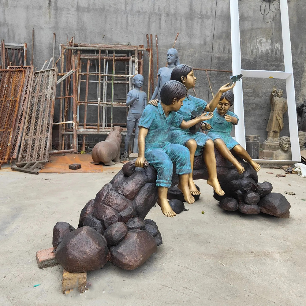 Estatua de niños sentados sobre un tronco